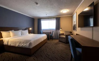 a hotel room with a bed and a chair and a desk at Prestige Mountain Resort Rossland in Rossland