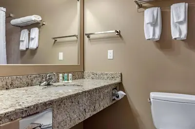 a bathroom with a sink and a toilet and a mirror at Quality Inn & Suites in Rimbey