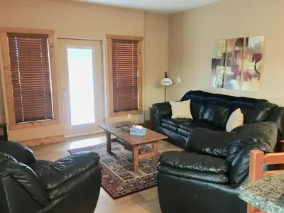 a living room with a leather couch and a table at Casa Del Mila Oro in Osoyoos
