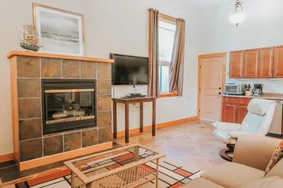 a living room with a fireplace and a tv at Cobble Wood and Bird Sanctuary Guest Houses in Tofino
