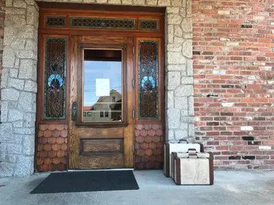 a wooden door with a suitcase in front of a brick building at The Inn at Tough City in Tofino