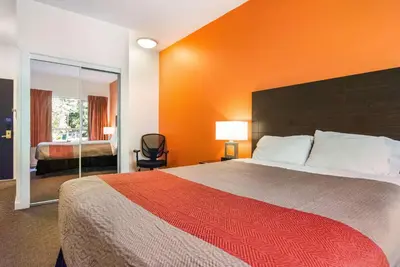 a bedroom with a large bed with an orange wall at Motel 6 Surrey, Bc in Surrey