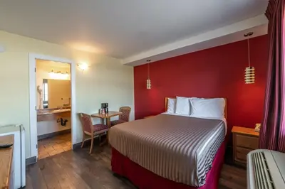 a hotel room with a bed with a red wall at Sahara Courtyard Inn Penticton in Penticton