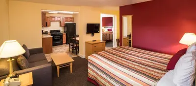 a hotel room with a bed and a kitchen at Sahara Courtyard Inn Penticton in Penticton