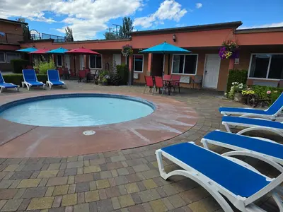 a patio with chairs and a swimming pool with tables and chairs at Sahara Courtyard Inn & Suites Osoyoos in Osoyoos