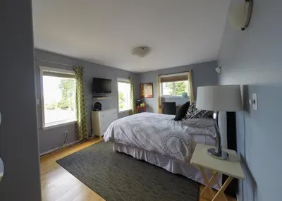 a bedroom with a bed and a table with a lamp at Money Pennies Bed and Breakfast in Campbell River