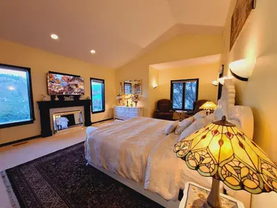 a bedroom with a large bed and a fireplace at Villa Bellissimo FranTalia - Résidence & Galleriséum in Kelowna