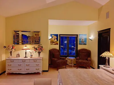 a bedroom with a bed and two chairs and a dresser at Villa Bellissimo FranTalia - Résidence & Galleriséum in Kelowna