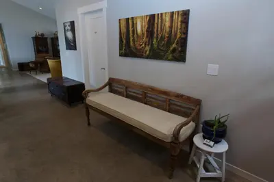 a bench in a room with a painting on the wall at Halfmoon Haven Beach Cottage or Oceanview Suite in Halfmoon Bay