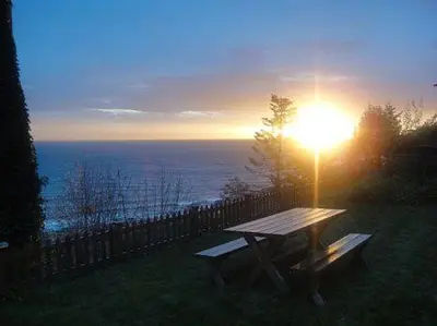 a picnic table with the sun setting over the ocean at Edgewater Motel in Oyster Bay