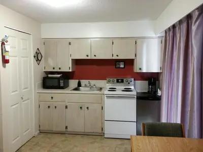a kitchen with white cabinets and a white stove top oven at Edgewater Motel in Oyster Bay