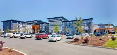 a parking lot with cars parked in front of a building at Sandman Signature Langley Hotel in Langley