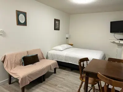a room with a bed and a chair and a table at Empire Motel in Penticton