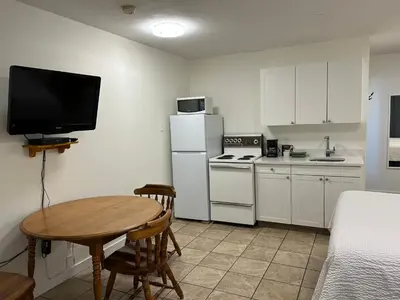 a small kitchen with a table and a television at Empire Motel in Penticton