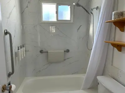 a white bathroom with a shower and a tub at Empire Motel in Penticton