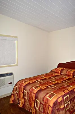 a bedroom with a bed and a window at Centre Suite Inns Motel in Bonnyville