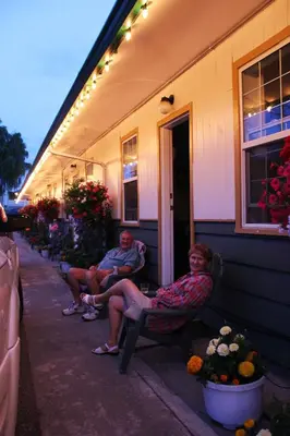 two people sitting on chairs on the side of a house at Boundary Motel in Osoyoos