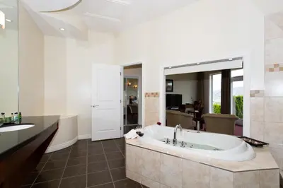 a bathroom with a tub and a large mirror at Shiraz Villa in Osoyoos