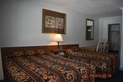 a hotel room with two beds and a table at Evening Star Motel in Greenwood