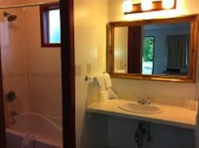 a bathroom with a sink and a mirror and a tub at Evening Star Motel in Greenwood