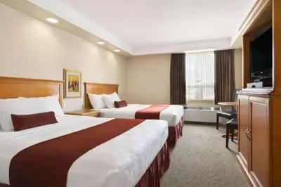 a hotel room with two beds and a flat screen tv at Travelodge by Wyndham Spruce Grove in Spruce Grove