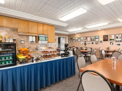 a cafeteria with a buffet line with tables and chairs at Travelodge by Wyndham Spruce Grove in Spruce Grove