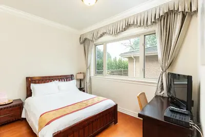 a bedroom with a bed and a television and a window at An Yang House in Burnaby