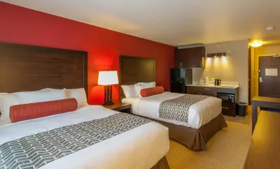 two beds in a hotel room with red walls at The Kanata Inns Invermere in Invermere
