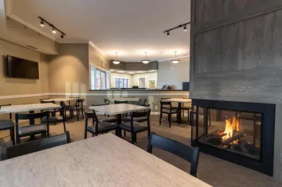 a dining room with tables and a fireplace at BCM Inns Fort McMurray - Downtown in Fort McMurray