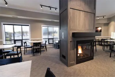 a fireplace in a dining room with tables and chairs at BCM Inns Fort McMurray - Downtown in Fort McMurray