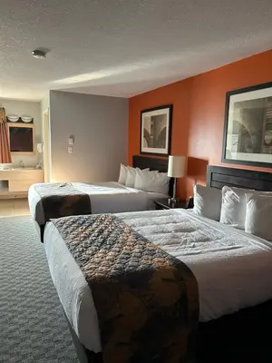 two beds in a hotel room with orange walls at BCMInns - Coleman in Coleman