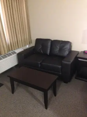 a living room with a black leather couch and a table at BCMInns - Peace River in Peace River