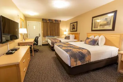 a hotel room with two beds and a flat screen tv at BCMInns - Fort McMurray - Rusty's in Fort McMurray