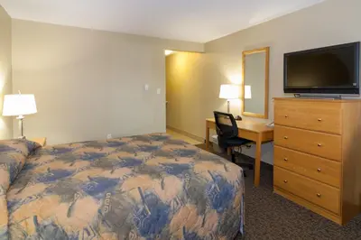 a hotel room with a bed and a desk and a television at BCMInns - Fort McMurray - Rusty's in Fort McMurray