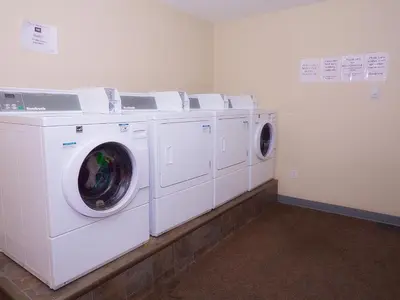 a laundry room with three washing machines in it at BCMInns - Fort McMurray - Rusty's in Fort McMurray