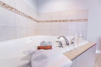a bathroom with a bath tub with glasses and towels at The Kanata by BCMInns - Hinton in Hinton
