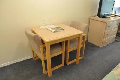a small wooden table with chairs and a television at Summerland Motel in Summerland