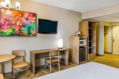 a room with a bed and a desk and a tv at Days Inn & Suites by Wyndham West Edmonton in Edmonton