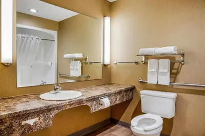 a bathroom with a toilet and a sink and a mirror at Days Inn & Suites by Wyndham West Edmonton in Edmonton