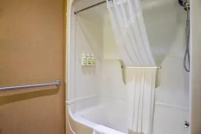 a bathroom with a shower with a white tub at Days Inn & Suites by Wyndham West Edmonton in Edmonton