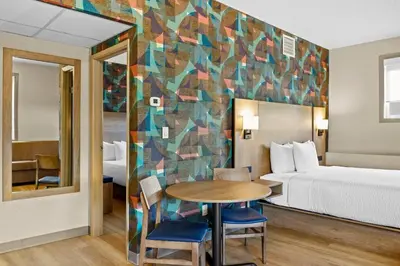 a hotel room with a bed and a table and chairs at Days Inn & Suites by Wyndham West Edmonton in Edmonton