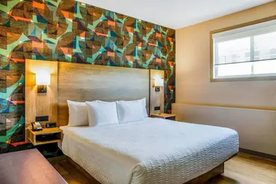 a hotel room with a bed and a colorful wall at Days Inn & Suites by Wyndham West Edmonton in Edmonton