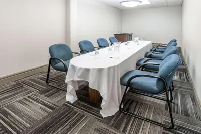 a conference room with a white table and blue chairs at Ramada by Wyndham Edmonton South in Edmonton