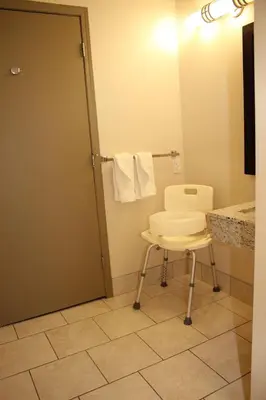a bathroom with a white chair and a mirror at Ramada by Wyndham Edmonton South in Edmonton