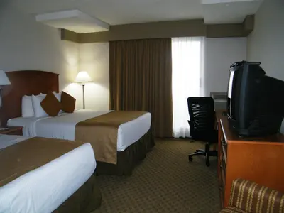 a hotel room with two beds and a flat screen tv at Ramada by Wyndham Edmonton South in Edmonton