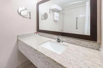 a bathroom with a sink and a large mirror at Ramada by Wyndham Edmonton South in Edmonton