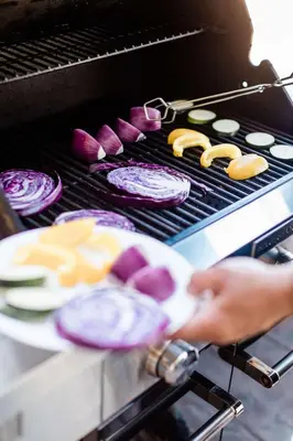 a person is cooking food on a grill at Coast Osoyoos Beach Hotel in Osoyoos