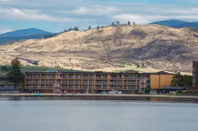 a large building with a mountain in the background at Coast Osoyoos Beach Hotel in Osoyoos