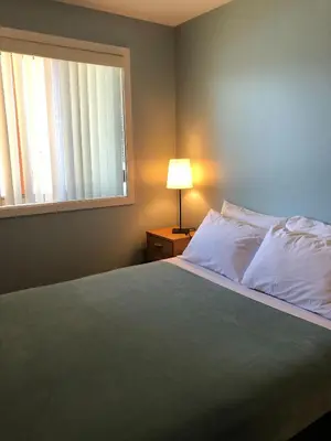 a bedroom with a bed and a window at Sun Beach Motel in Osoyoos
