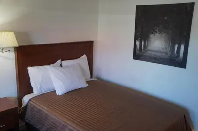 a bed with white pillows and a picture on the wall at Westward Inn & Suites in Langley